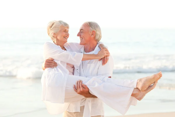 Man carrying his wife on the beach — Stock Photo, Image