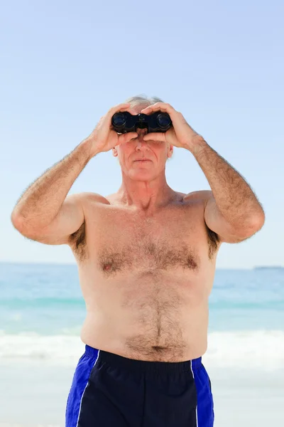 Senior mannen fågelskådning på stranden — Stockfoto