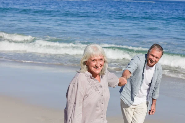 Äldre par promenerar på stranden — Stockfoto