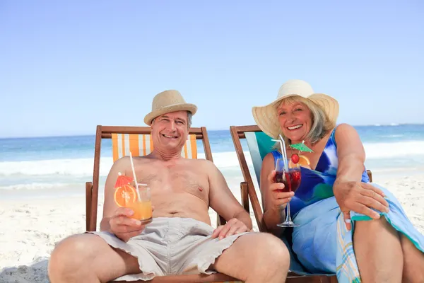 Mature couple sitting on deck chairs — Stock Photo, Image