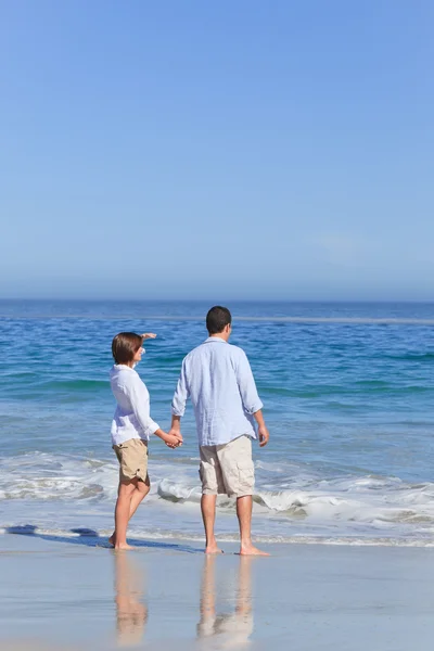 Paar spaziert am Strand unter der Sonne — Stockfoto