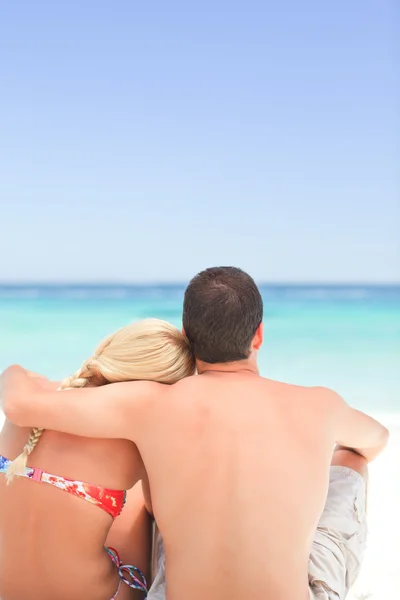 Мужчина обнимает свою девушку, пока они смотрят на море — стоковое фото