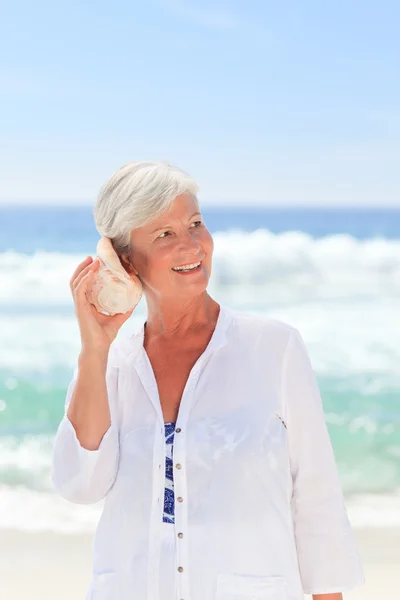 Зрелая женщина слушает свою скорлупу — стоковое фото