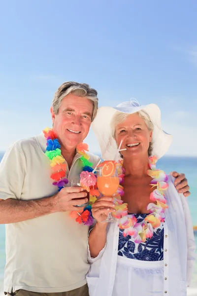 Пожилая пара пьет коктейль на пляже — стоковое фото