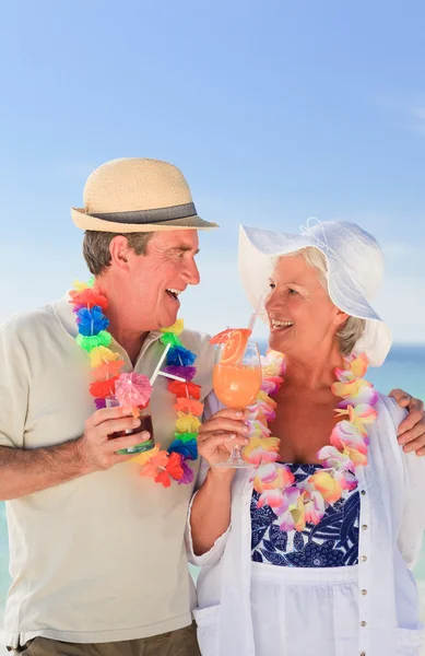 Casal de idosos bebendo um coquetel na praia — Fotografia de Stock