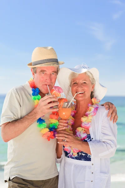 Coppia anziana che beve un cocktail in spiaggia — Foto Stock