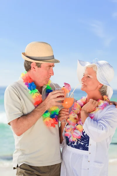 老夫妇在沙滩上喝一杯鸡尾酒 — 图库照片