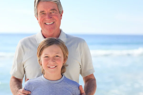Farfar med sitt barnbarn på stranden — Stockfoto