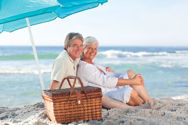 Äldre par picniking på stranden — Stockfoto