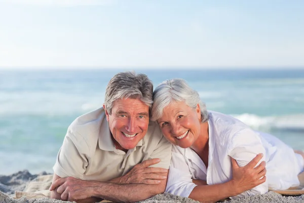 Mature couple lying down on the beach — Stock Photo, Image