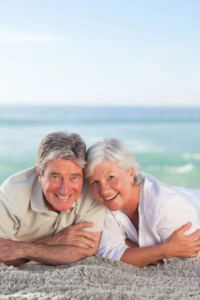 Ouder paar liggen op het strand — Stockfoto