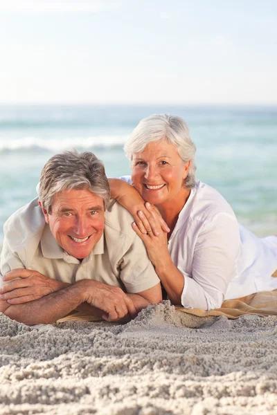 Elderly couple lying down on the beach — Stock Photo, Image