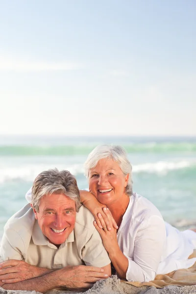 Bejaarde echtpaar liggen op het strand — Stockfoto