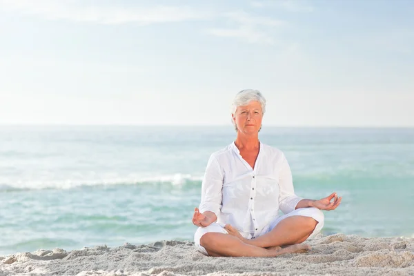 Mulher madura praticando ioga na praia — Fotografia de Stock