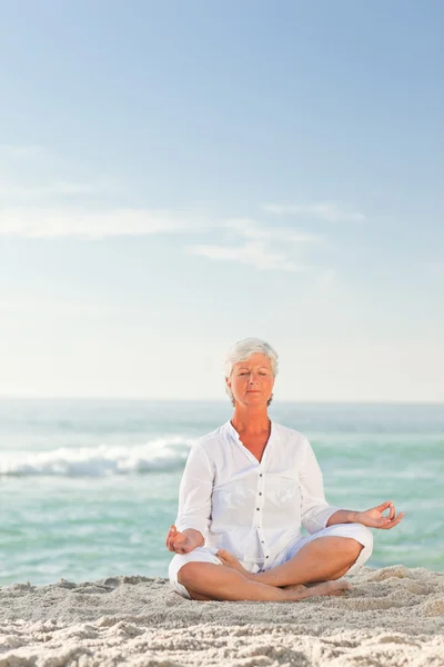 Starsza kobieta praktykowania jogi na plaży — Zdjęcie stockowe