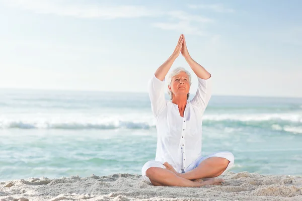 Mulher madura praticando ioga na praia — Fotografia de Stock