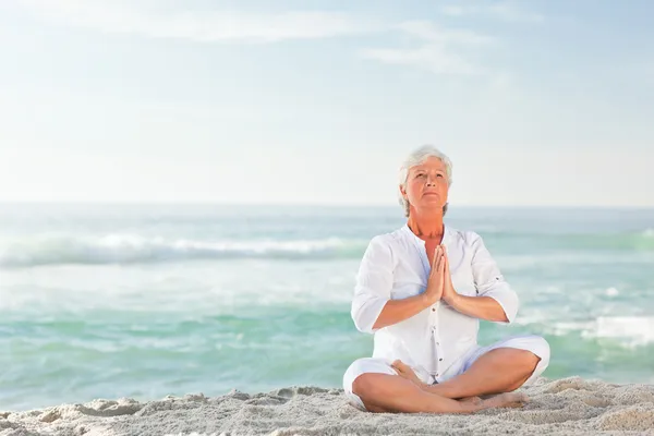 Зрелая женщина практикует йогу на пляже — стоковое фото