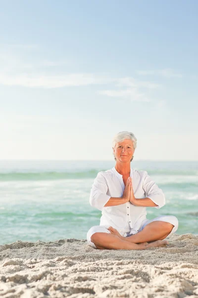 Reife Frau praktiziert Yoga am Strand — Stockfoto