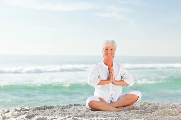 Mujer madura practicando yoga en la playa — Foto de Stock