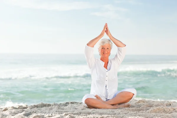 Volwassen vrouw beoefenen van yoga op het strand — Stockfoto