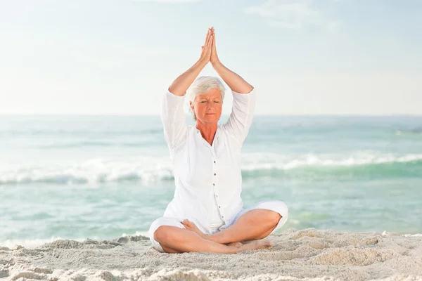 Reife Frau praktiziert Yoga am Strand — Stockfoto