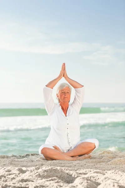 Mujer madura practicando yoga en la playa — Foto de Stock