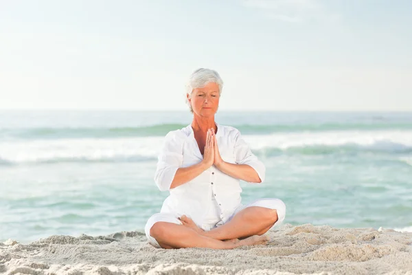Zralá žena cvičí jógu na pláži — Stock fotografie