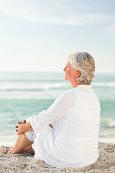 Vrouw die is zittend op het strand — Stockfoto