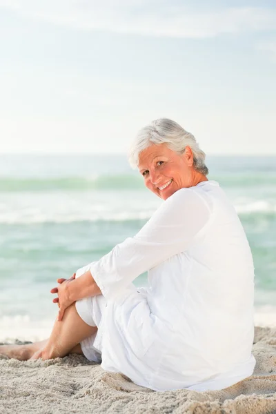 Женщина, которая сидит на пляже — стоковое фото