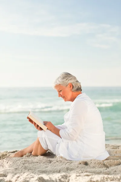 Yaşlı kadın sahilde ona kitap okuma — Stok fotoğraf