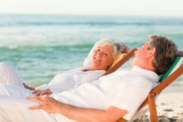 Casal de idosos relaxando em suas cadeiras de praia — Fotografia de Stock