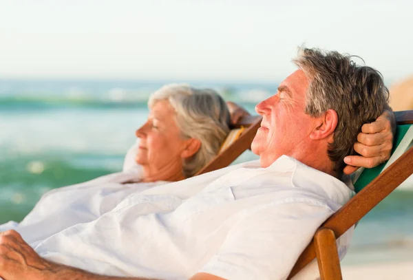Äldre par kopplar av i sina solstolar — Stockfoto