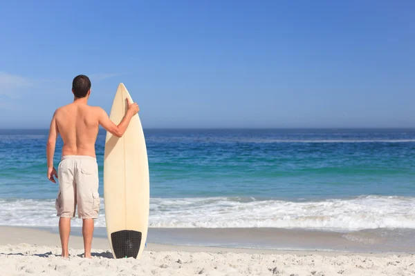 Człowiek wirth jego deskę surfingową na plaży — Zdjęcie stockowe