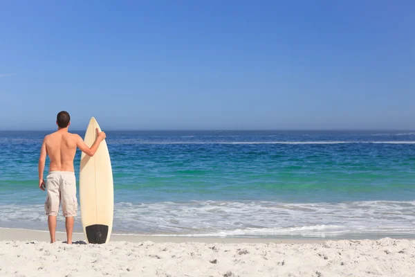 Człowiek wirth jego deskę surfingową na plaży — Zdjęcie stockowe