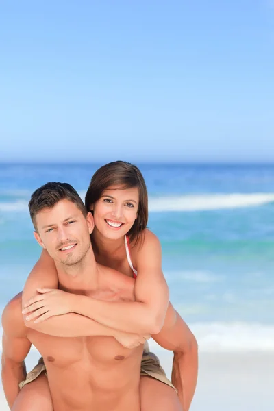 Bello uomo avendo moglie un cavalluccio su il spiaggia — Foto Stock