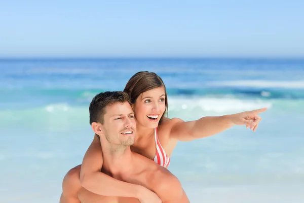 Przystojny mężczyzna mając żonę piggyback na plaży — Zdjęcie stockowe