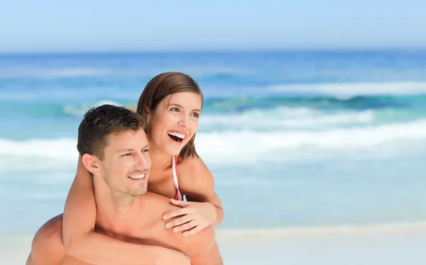 Man har fru en piggyback på stranden — Stockfoto