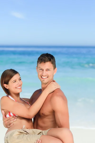 男子携带他的妻子在海滩上 — 图库照片