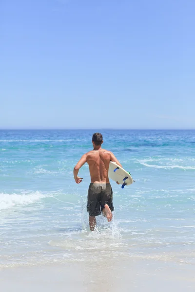 Człowiek działa na plaży z jego deskę surfingową — Zdjęcie stockowe