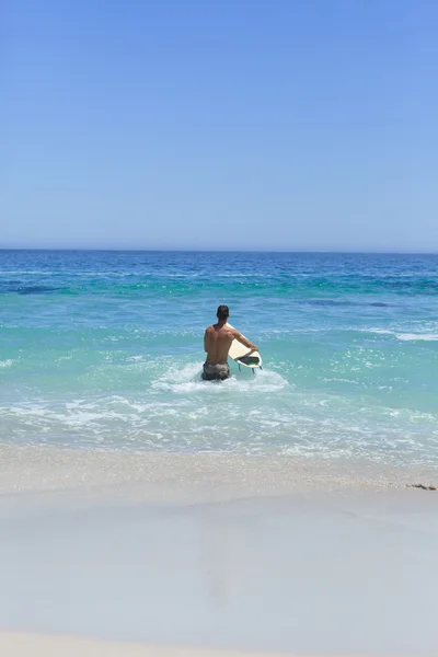 Чоловік біжить на пляжі зі своїм дошкою для серфінгу — стокове фото