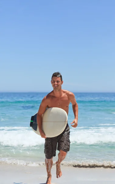 Homem correndo na praia com sua prancha de surf — Fotografia de Stock