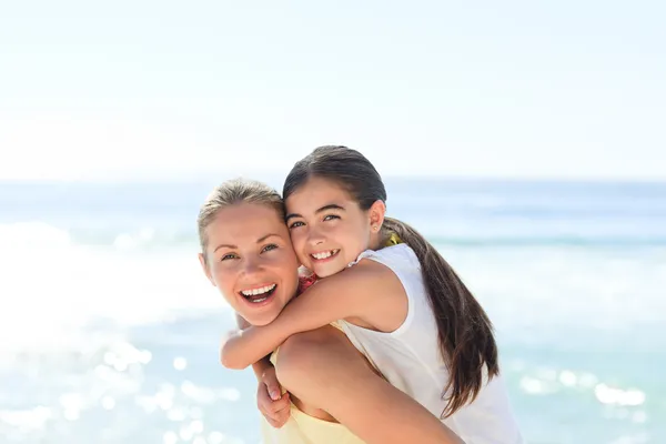Madre teniendo una hija a cuestas en la playa —  Fotos de Stock