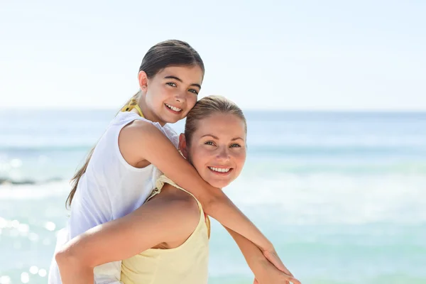 Mor ha dotter en piggyback på stranden — Stockfoto