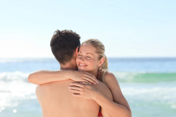 Vrouw haar vriendje knuffelen op het strand — Stockfoto