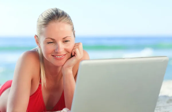 Mulher encantadora trabalhando em seu laptop na praia — Fotografia de Stock