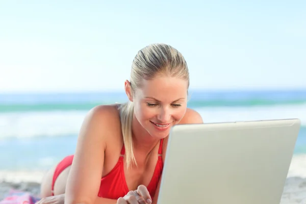 Милая женщина работает над своим ноутбуком на пляже — стоковое фото
