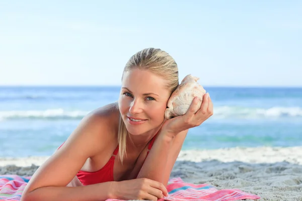 Woman listening to a shell — Stock Photo, Image