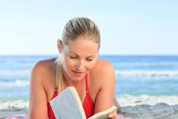 Bedårande kvinna läser en bok på stranden — Stockfoto