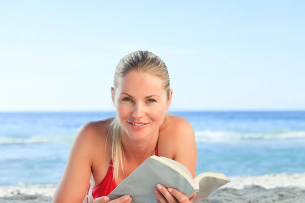 Очаровательная женщина читает книгу на пляже — стоковое фото