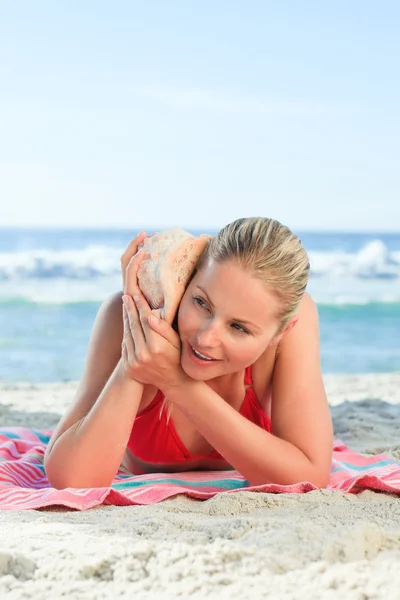 Woman listening to a shell — Stock Photo, Image